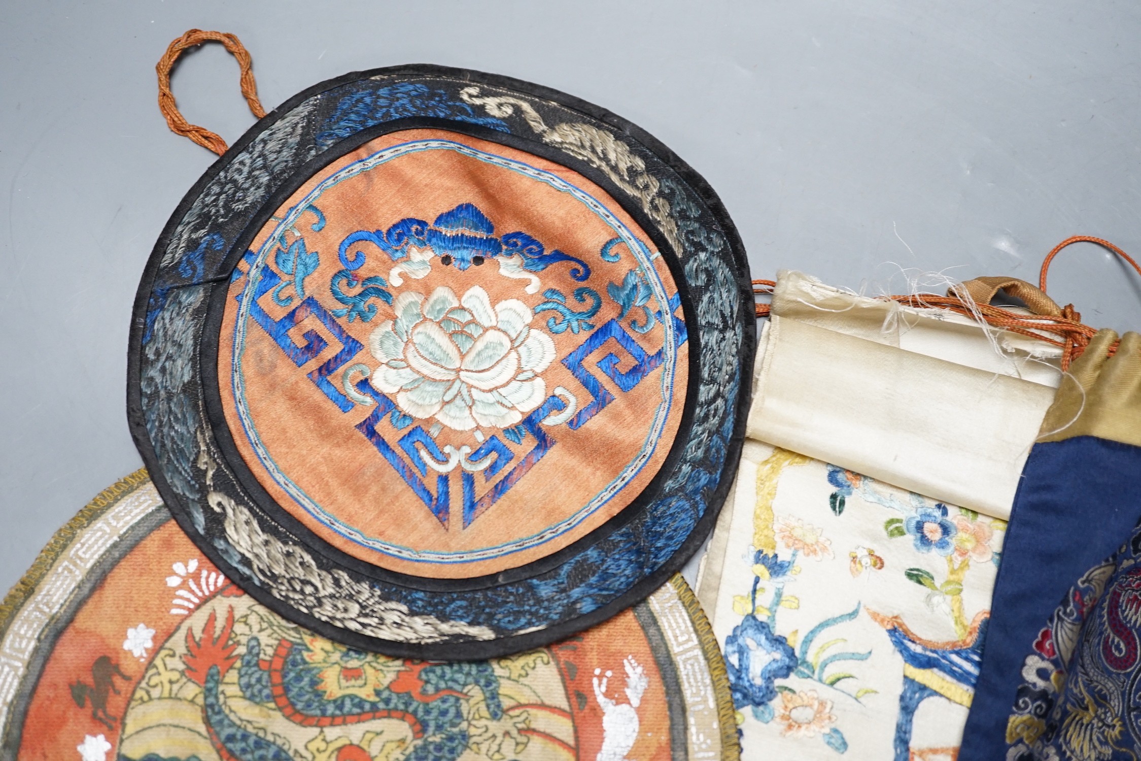 A Chinese embroidered sleeve band, two mats and a woven brocade bag.